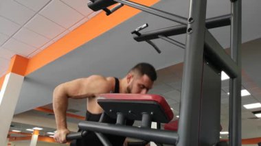 Spor eğitim sırasında genç kaslı adam şınav çubukları üzerinde gerçekleştirir.