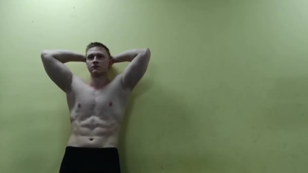 Hombre atlético posando contra la pared en el gimnasio — Vídeo de stock