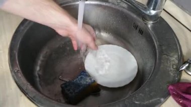 Evin erkeklerin elleri çalışan su çekim altında yemekleri yıkamak