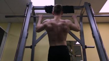 Genç adam spor salonunda fitness meşgul. Atlet barda çekildi