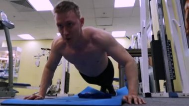 Genç spor adam spor salonunda şınav gerçekleştirir. Atlet Fitness meşgul