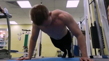 Genç spor adam spor salonunda şınav gerçekleştirir. Atlet Fitness meşgul