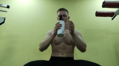 İçme suyu spor salonunda genç adam. Adam bir protein shake kullanır