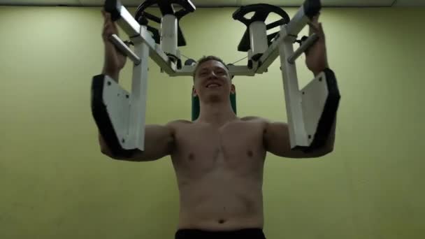 Молодой человек тренирует грудные мышцы в тренажерном зале, занимается фитнесом — стоковое видео