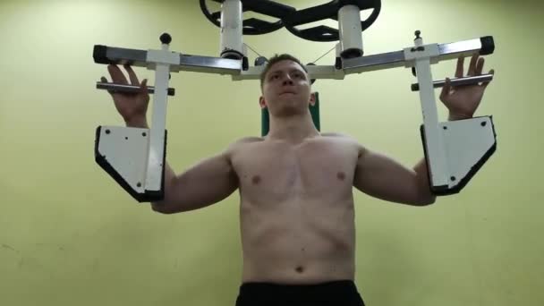 Young man trains pectoral muscles in the gym, doing fitness — Stock Video