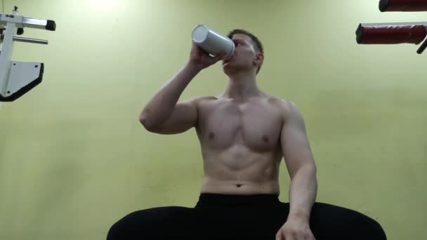 Jeune homme buvant de l'eau au gymnase. Il utilise un shake protéiné. — Video