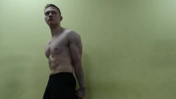 Athletic man posing against the wall in the gym — Stock Video