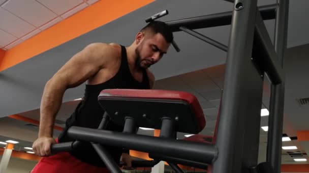 Молодой мускулистый человек во время тренировки в тренажерном зале отжимается на барах — стоковое видео