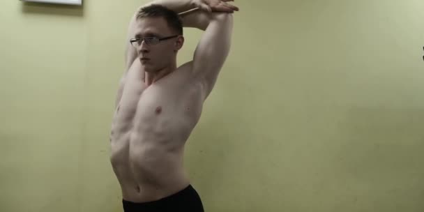 Man stretching arm voor gym workout. Fitness sterke mannelijke atleet staande indoor warming up. — Stockvideo