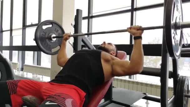 RUSIA, TOGLIATTY - 23 DE FEBRERO DE 2019: Muscular man on bench press. El tipo entrena en el gimnasio con una barra — Vídeo de stock