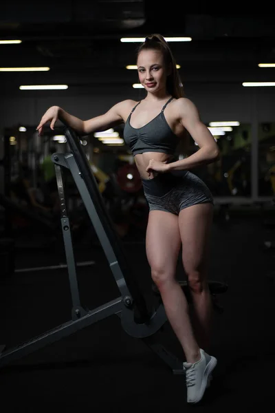 Chica de fitness posando en el gimnasio en el banco mostrando su cuerpo —  Fotos de Stock