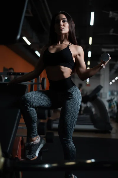Dziewczynka fitness pociągi biceps z hantlami w siłowni. — Zdjęcie stockowe