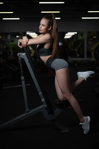 Fitness menina posando no ginásio no banco mostrando seu corpo — Fotografia de Stock