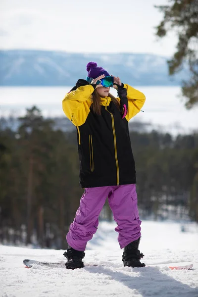Mulher posando em um snowboard. Desportos de Inverno. Menina em engrenagem em um snowboard — Fotografia de Stock