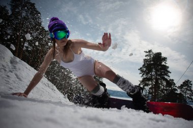 Mayoyla giyinmiş kız büyük bir hızla snowboard yaparken taşır. Kış spor