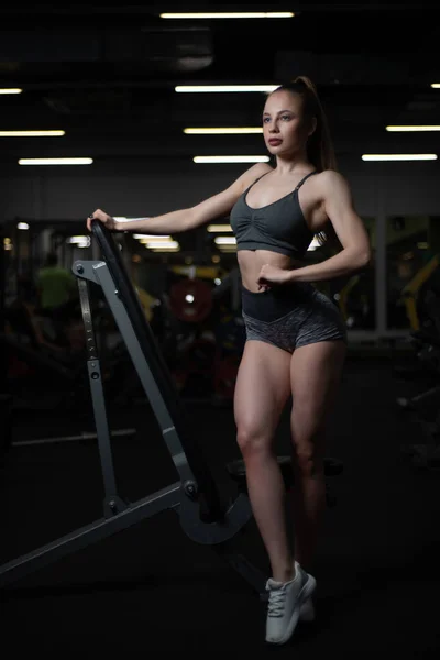 Chica de fitness posando en el gimnasio en el banco mostrando su cuerpo —  Fotos de Stock