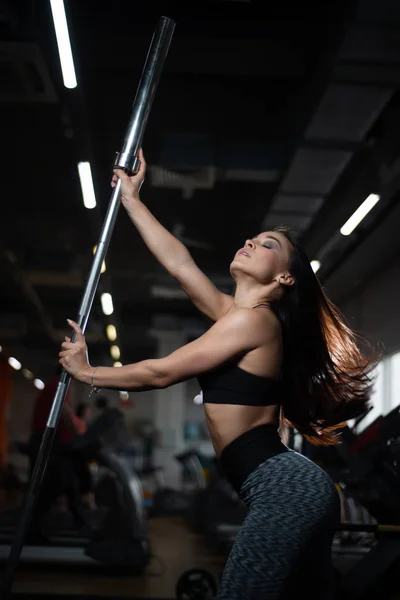 Meisje poseren in de sportschool, pronken haar lichaam, houden een barbell — Stockfoto