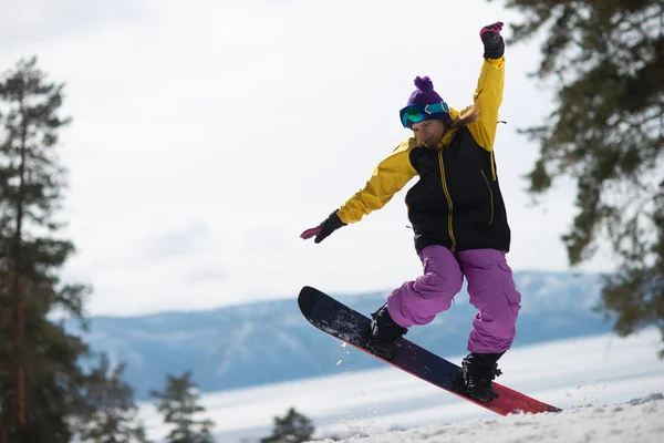 Mulher montando um snowboard salta. Desportos de Inverno. Menina em engrenagem em um snowboard — Fotografia de Stock