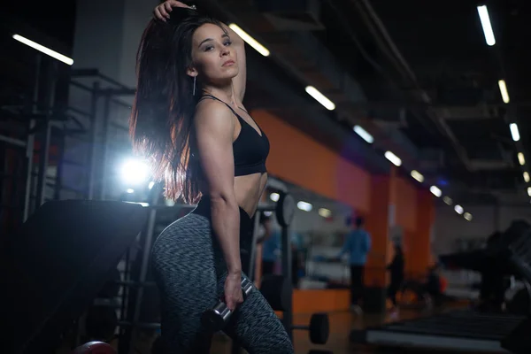 Chica de fitness entrena bíceps con pesas en el gimnasio . —  Fotos de Stock