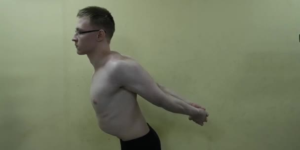 Uomo che si allunga il braccio prima dell'allenamento in palestra. Fitness forte atleta maschio in piedi riscaldamento interno . — Video Stock