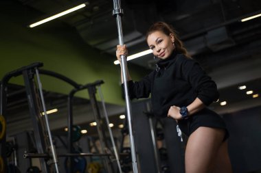 Spor salonunda, poz kız bir halter tutarak onun vücudundan gösterilen