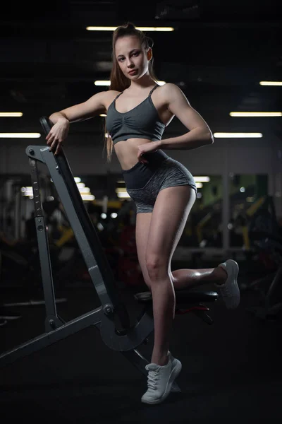 Fitness flicka poserar i gymmet på bänken visar hennes kropp — Stockfoto