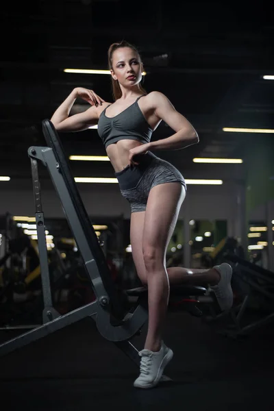 Fitness girl posing in the gym on the bench showing off her body — Stock Photo, Image