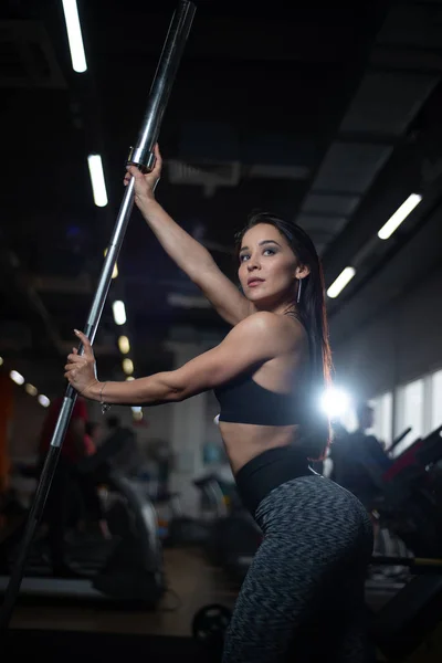 Meisje poseren in de sportschool, pronken haar lichaam, houden een barbell — Stockfoto