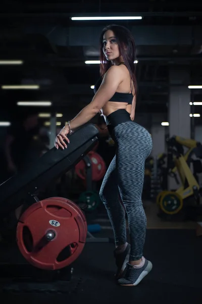 Fitness menina posando no ginásio, mostrando seu corpo e relaxante após um treino — Fotografia de Stock