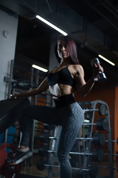 Fitness-Girl trainiert Bizeps mit Kurzhanteln im Fitnessstudio. — Stockfoto