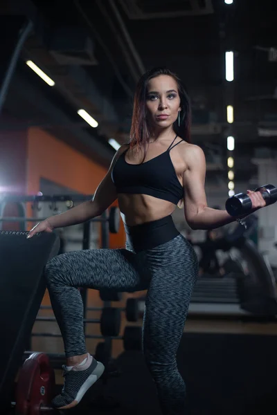Fitness meisje traint biceps met halters in de sportschool. — Stockfoto