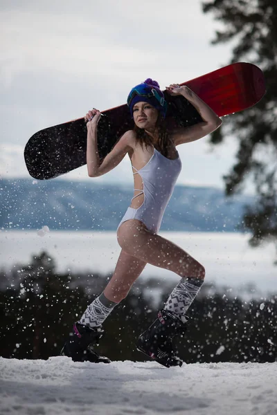 Woman dressed in a swimsuit posing with a snowboard in her hands. Winter sport — Stock Photo, Image