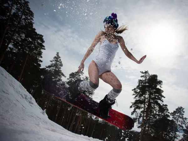 Frau auf einem Snowboard springt. Wintersport. Mädchen in Ausrüstung auf einem Snowboard — Stockfoto