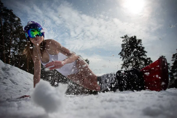 Chica vestida con un traje de baño se mueve con gran velocidad en una tabla de snowboard. Deportes de invierno — Foto de Stock