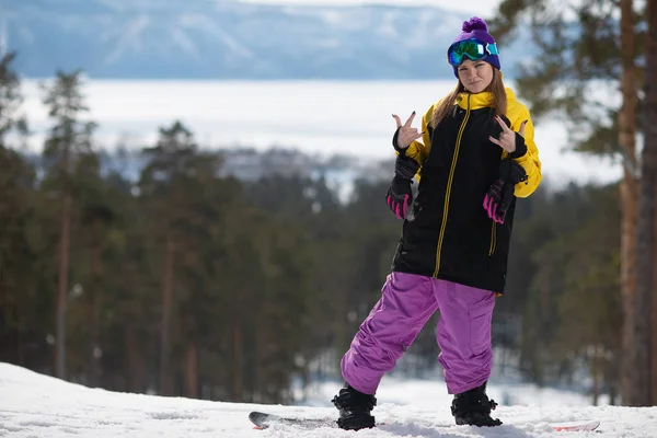 Frau posiert auf einem Snowboard. Wintersport. Mädchen in Ausrüstung auf einem Snowboard Stockbild