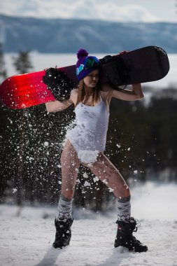 Çekici bir kadın onun elinde bir snowboard ile poz bir mayo giymiş. Kış sporları ve uçan kar