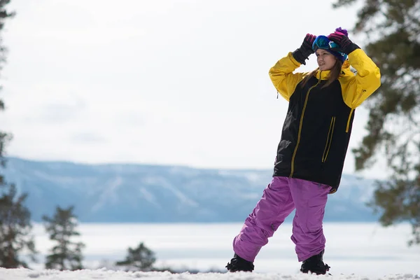 Frau posiert auf einem Snowboard. Wintersport. Mädchen in Ausrüstung auf einem Snowboard lizenzfreie Stockbilder