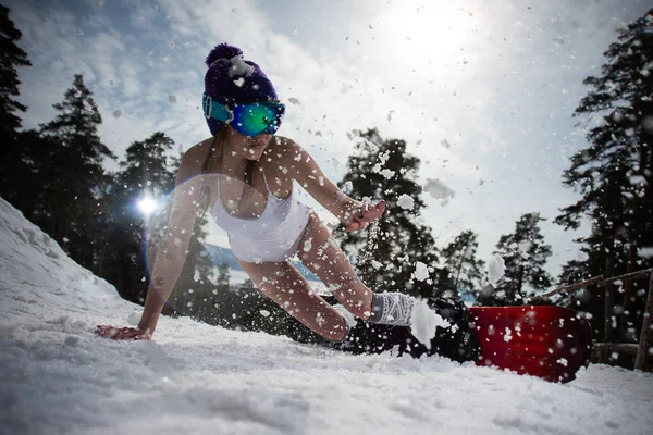 Dziewczyna ubrana w strój kąpielowy porusza się z dużą prędkością na snowboard. Sporty zimowe — Zdjęcie stockowe