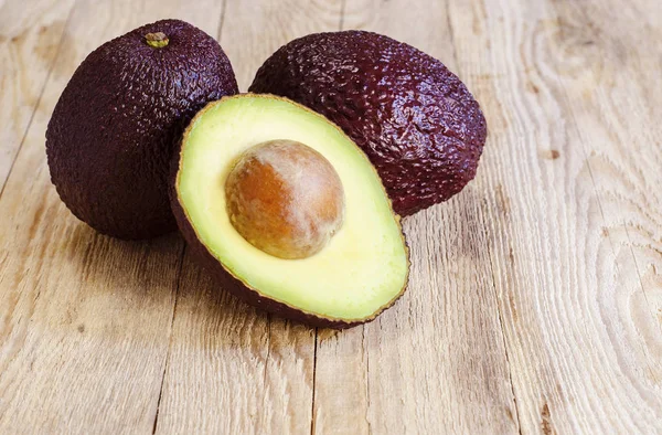 Avokado bütün ve ahşap arka plan üzerinde kesme
