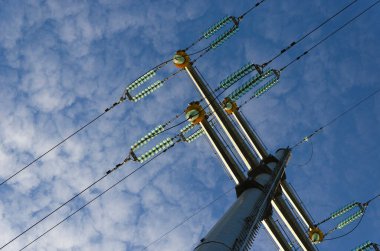 Bulutlu gökyüzüne karşı sütun ve elektrik hatları