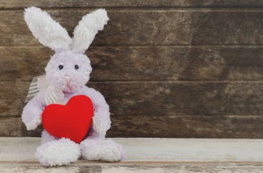 güzel tavşan bebek oturma ve ahşap masa n kırmızı kalp tutarak