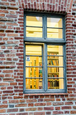 Kırmızı tuğla duvardaki bir pencereden kütüphane