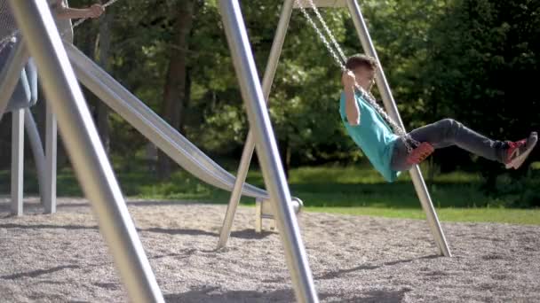 Crianças em baloiços no parque infantil — Vídeo de Stock