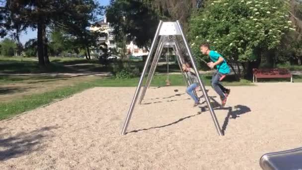 Niños en columpios en el parque infantil — Vídeos de Stock