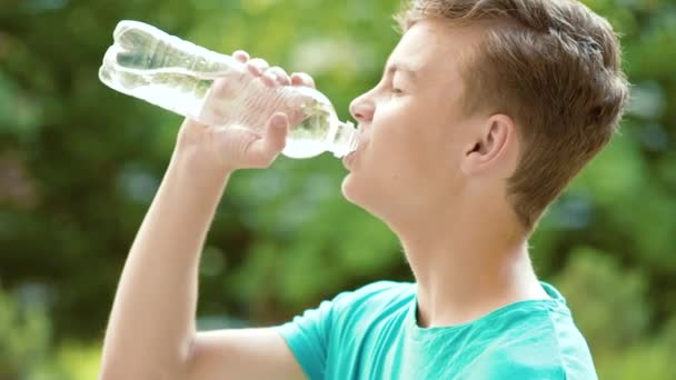 Мальчик-подросток пьет воду на открытом воздухе — стоковое видео