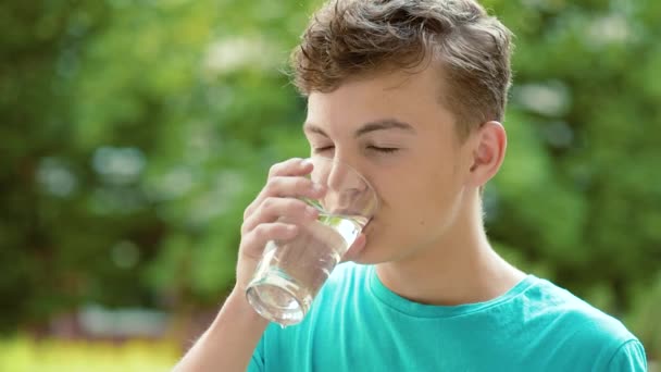 Teen pojke dricksvatten utomhus — Stockvideo