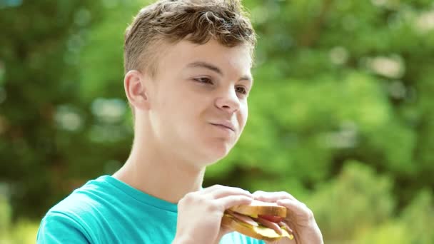 Мальчик-подросток ест сэндвич — стоковое видео