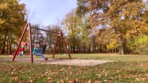 Niños en columpios en el parque infantil — Vídeos de Stock