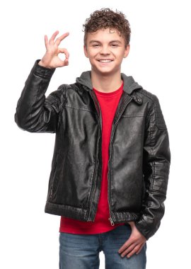 Siyah deri ceketli yakışıklı bir acımasız genç çocuk portresi. Çocuk Model beyaz arka plan üzerinde izole moda gülümseyerek. Komik genç ok jest yapma.