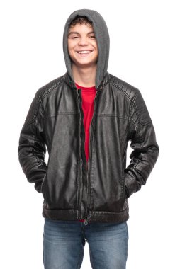 Portrait of a Handsome brutal Teen Boy in a black Leather Jacket with Hood. Smiling fashion Child Model isolated on White background. Funny Teenager with Hands in Pockets.